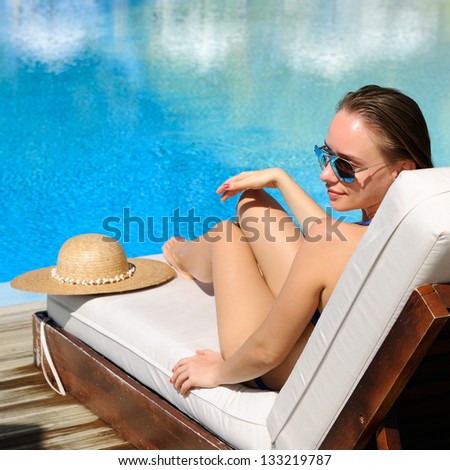 Woman relaxing in chaise lounge at the poolside
