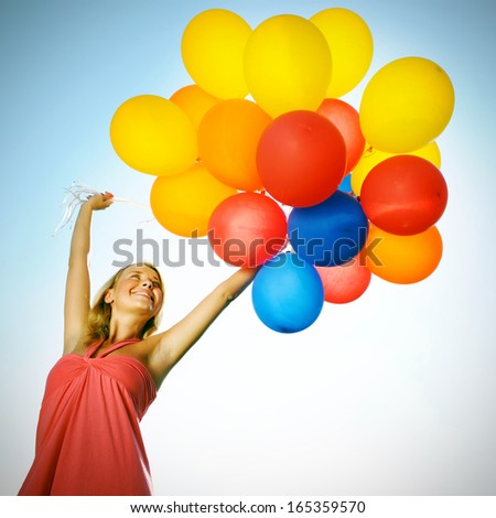 Woman Holding Balloons Against Sun And Sky
