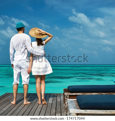 Couple On A Tropical Beach Jetty At Maldives