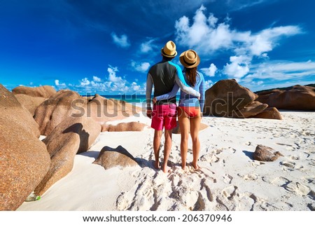 Couple on a tropical beach at Seychelles wearing rash guard