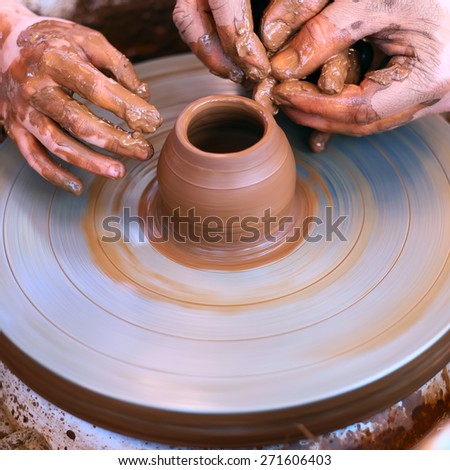 Potter\'s hands guiding child\'s hands to help him to work with the pottery wheel