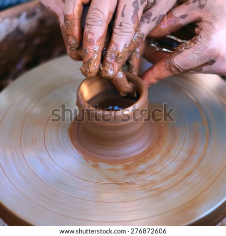 Potter\'s hands guiding child\'s hands to help him to work with the pottery wheel