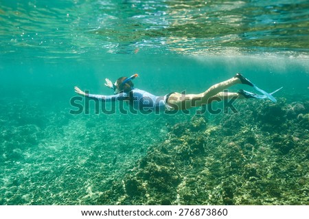 Woman with mask snorkeling in clear water