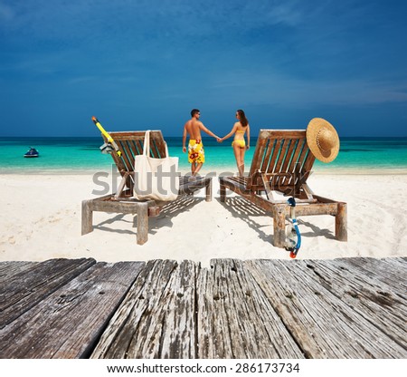 Couple in yellow relax on a tropical beach at Maldives