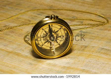 Old style gold compass on papyrus background