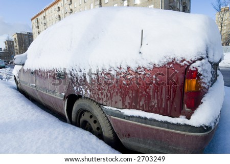 Car covered with snow, city landscape