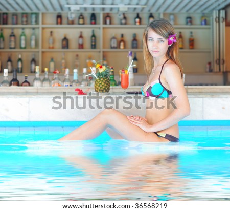 Girl in tropical pool bar with cocktail. Reflection in water.