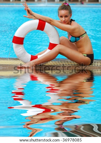 Girl near tropical pool with life saving buoy. Reflection in water.
