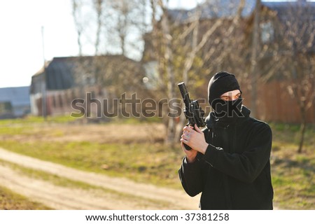 Gunman in black mask holding gun with silencer