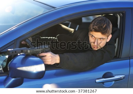 Gunman in car holding gun with silencer