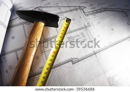 Hammer and measure tape over house plan blue prints