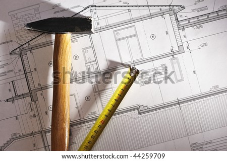 Hammer and measure tape over house plan blue prints