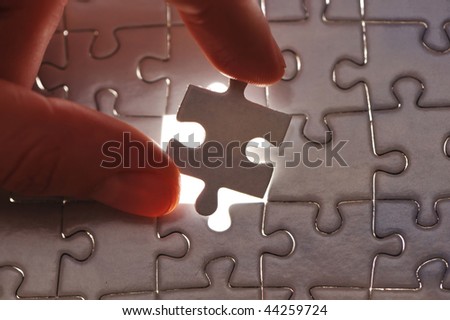 Hand placing missing puzzle piece with shallow DOF
