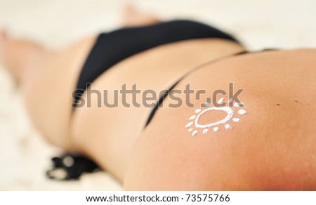 Sunscreen lotion over tan woman skin made as sun shape