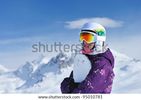Woman holding snowboard with mountains in background. No brandnames or copyright objects.