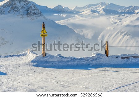 Off-piste sign in french language at Alpine winter mountain landscape with low clouds. French Alps covered with snow in sunny day. Val-d\'Isere, France