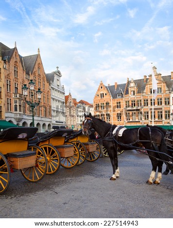 Horse-drawn carriages on the Old Market square (Grote markt). Bruges, Belgium