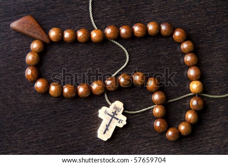 handmade rosary beads and cross on dark wooden background