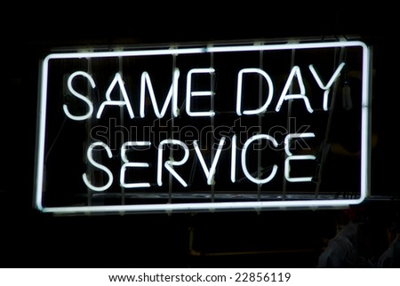 Neon sign advertising same day service in the window of a Harlem, New York City dry cleaning store