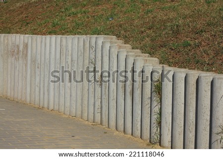 Retaining wall of concrete cylindrical palisade with paving of sidewalks