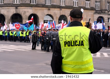 Police officer talking on a radio during an anti-government demonstration in Warsaw Poland on 7 Oct 2006 (Blue March by Platforma Obywatelska). Purposely taken with a shallow DOF not to detail faces.