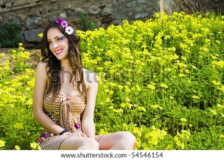 Hippie girl and happy sitting in a field of flowers smiling