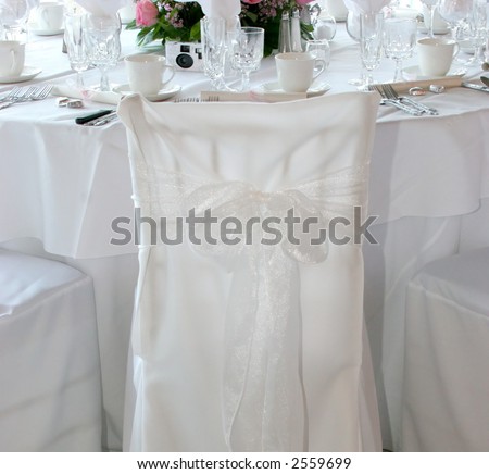 elegantly decorated chair in banquet hall with decorated table in background