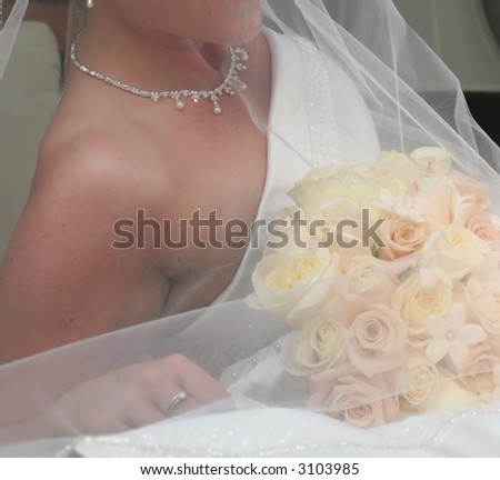 detail of bride holding bouquet  showing delicate lines in upper bodice of wedding dress and shoulder