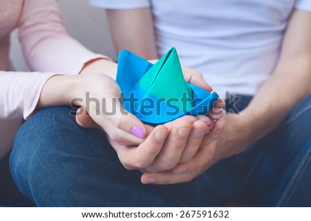 man and woman keeping paper ship as a symbol of future newborn child