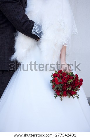flower bouqUet in hands of . groom embracing bride