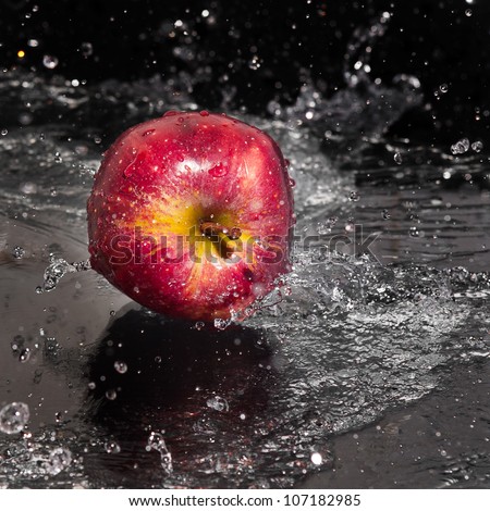 Fresh an apple in streaming splash water on black background