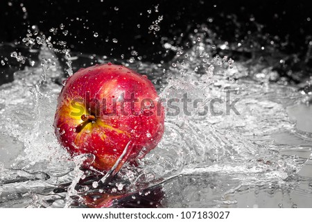 Fresh an apple in streaming splash water on black background