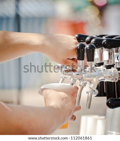 Pouring beer to plastic glass from beer tap