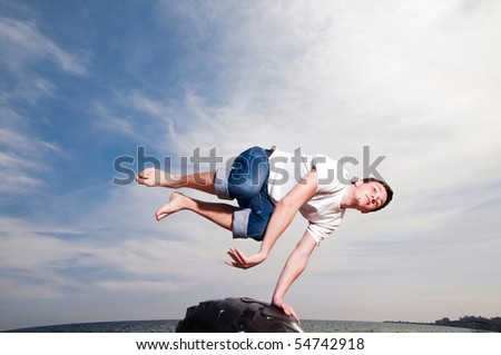 Young man jumping on the beach on sky background
