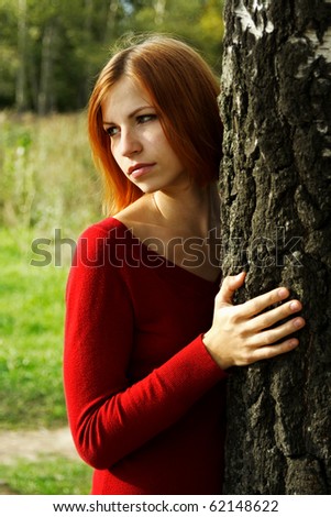 beauty girl in red dress snuggle up to tree, half body, looking at side