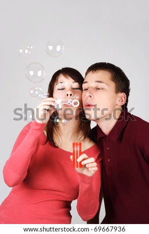 young brunette man and woman in red shirts blowing out soap bubbles