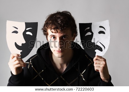 serious man holding two emotion theater masks and looking at camera