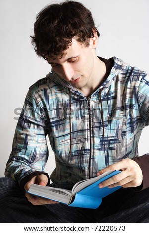 young man in sport clothes sitting and reading book in blue cover