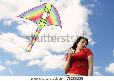 Young girl in red shirt flying kite, blue sky