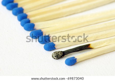 Macro closeup of a group of matches, one match burned, isolated on white background
