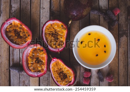 Close up yellow color passion fruit pulp and seed in small ceramic bowl isolated on BROWN board, andied fruit, plate with jam