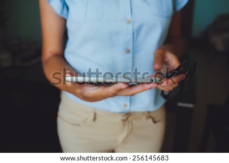 Businesswoman uses digital tablet. The tablet has a gray case and a glass screen. The woman in blue shirt.