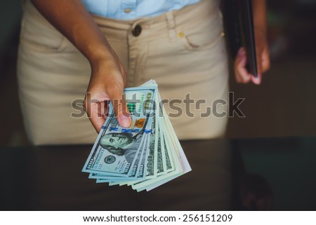 Money in human hands, women giving a lot of 100 dollars, with business folders , on a black background