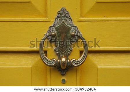 bronze door knocker\
bronze door knocker on a yellow door