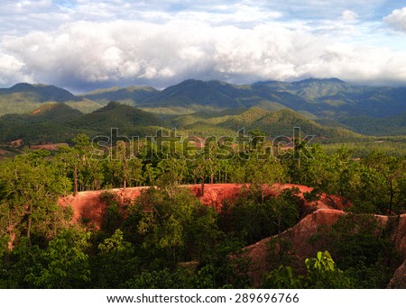 Pai Canyon in the late afternoon with god rays shining through dark clouds and a beautiful red sand stone.