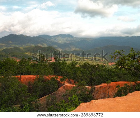 Pai Canyon in the late afternoon with god rays shining through dark clouds and a beautiful red sand stone.
