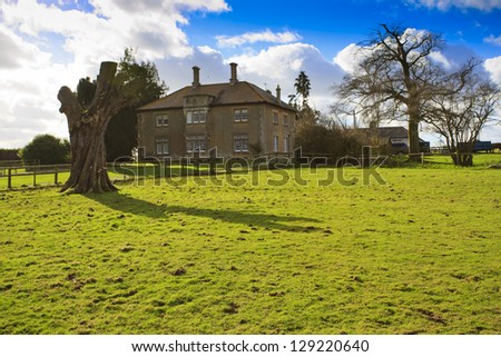 Large traditional British Farmhouse with dead tree in the countryside near Swindon