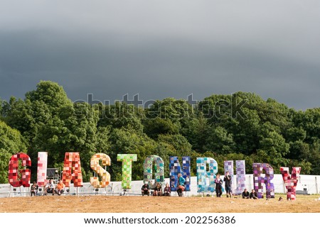 GLASTONBURY, UK - JUNE 28: Festival goers look at a panorama over the festival with a large Glastonbury sign at Glastonbury Festival on 28th June, 2014 at Pilton Farm, Somerset.