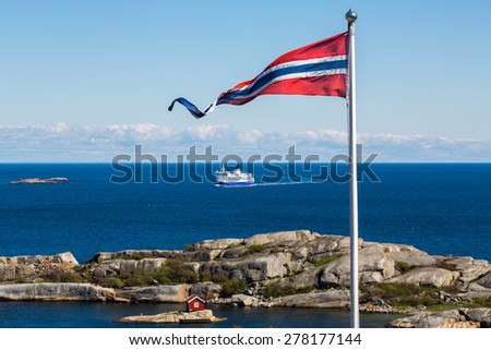Norwegian flag with a small red cabin and an unmarked ferry in the background