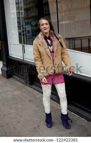 Young woman with pink top and fur coat on the street.